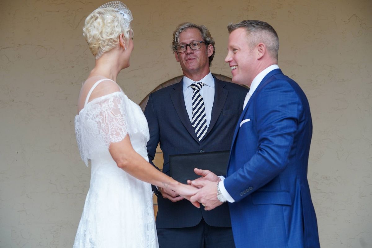 A bride and groom hold hands and exchange vows with their officiant